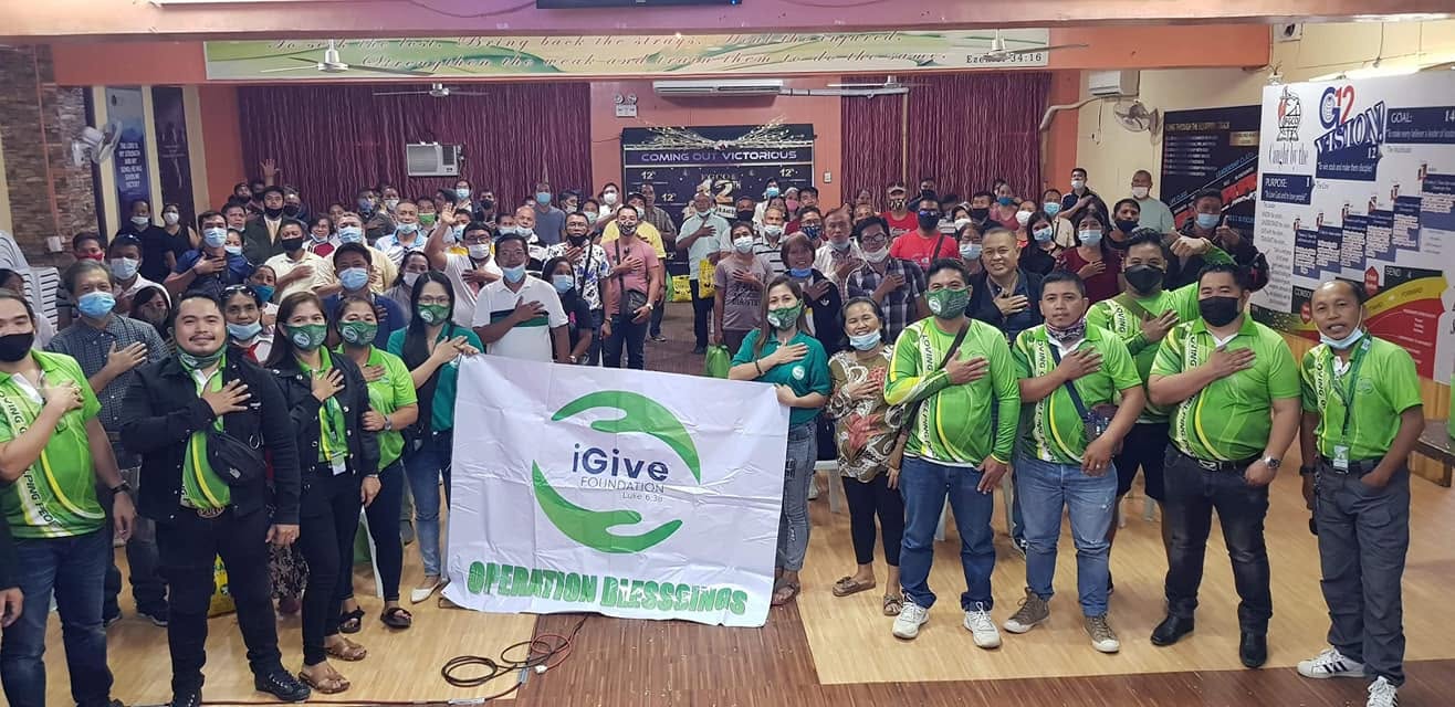 I Give Foundation community members gathered behind an Operation Blessings banner